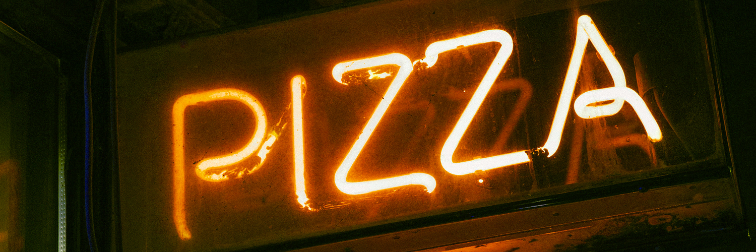 Image of a neon sign that reads “Pizza”.