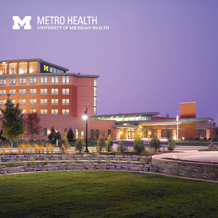 Image of the Metro Health University of Michigan Health building. Text and the top left corner reads “Metro Health University of Michigan Health” with the logo to the left.