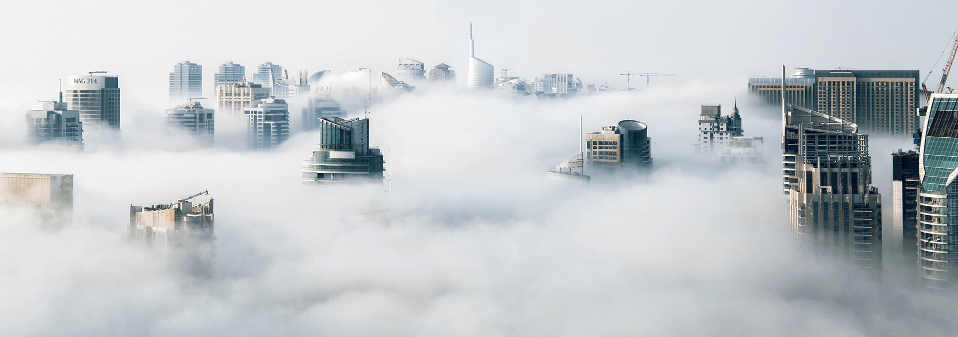 The tallest buildings of a cityscape peeking above a bed of low-hanging clouds